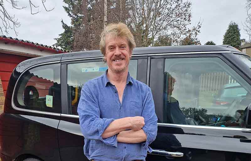 Standing arms crossed by his London Black Cab.